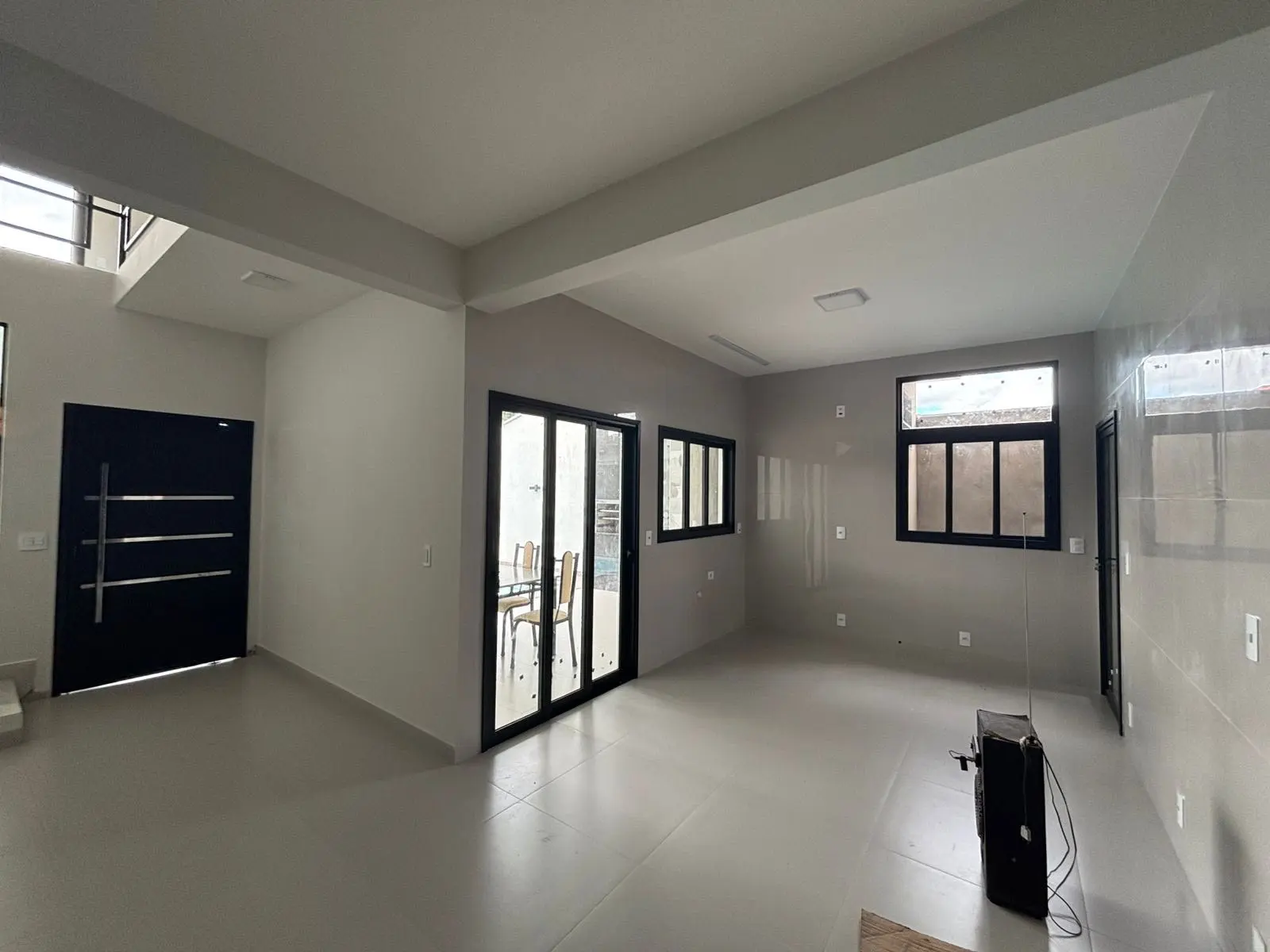 Sala ampla com porta pivotante, porta de correr e janelas em alumínio preto