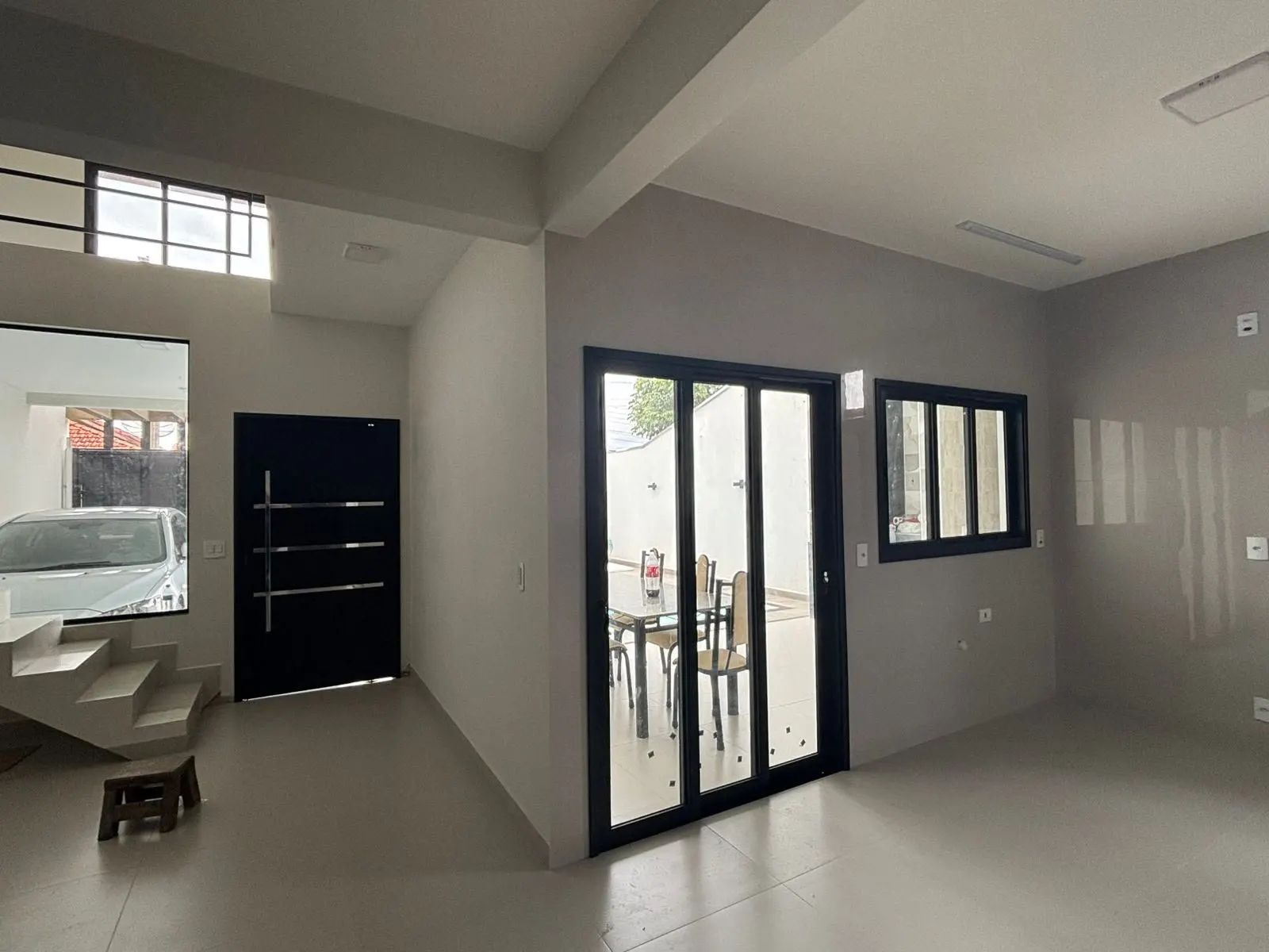 Sala integrada com porta de vidro de correr e esquadrias de alumínio preto instaladas pela BomBox Vidraçaria